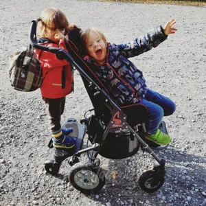 Copil utilizand caruciorul de reabilitare Swifty 1 in exterior